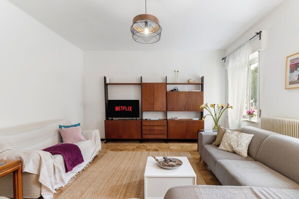 A living room with a sofa, a coffee table, a TV, and a wooden cabinet.
