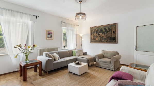Un salon avec un canapé, un fauteuil, une table basse et un tableau accroché au mur.