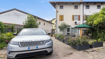 A Range Rover parked in front of a building with a paved driveway, surrounded by potted plants and a small outdoor seating area.