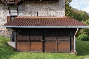 A building with a stone facade, a tiled roof, and a covered garage with wooden doors. - Wooden Stories - Netflix, Wi-fi, Pet Friendly (Socchieve)