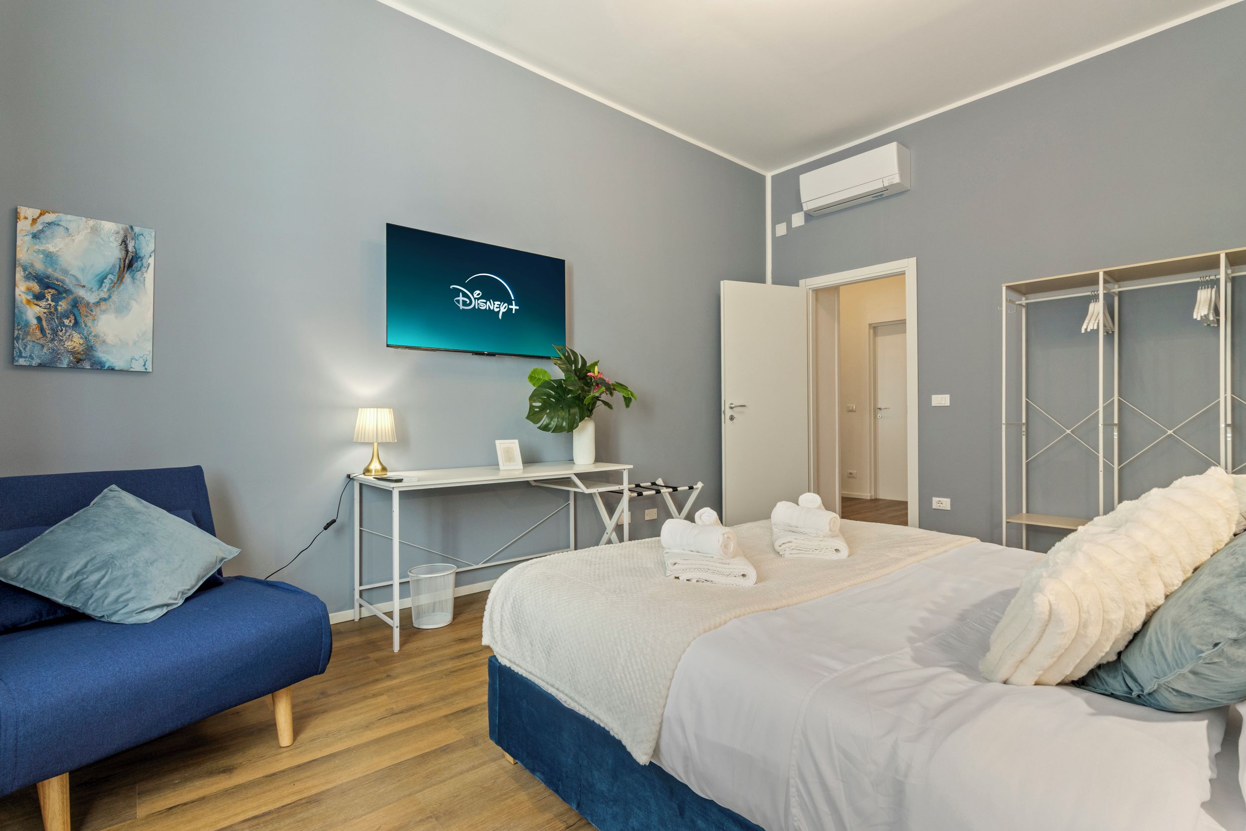 Ein modernes Hotelzimmer mit einem Bett, einem Schreibtisch, einem Fernseher und einem Kleiderschrank.