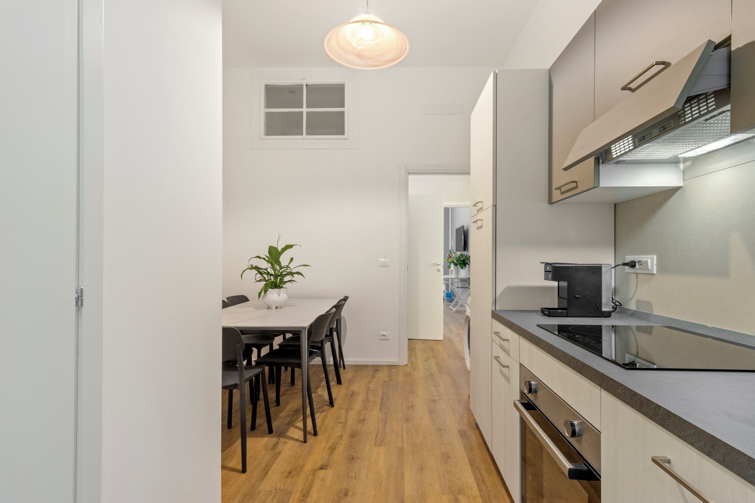 Eine moderne Küche mit Essbereich, Holzboden und einem Blumentopf.