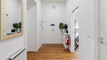 Ein Flur mit weißen Wänden, Holzboden, einer weißen Tür am Ende und einem an der Wand befestigten Feuerlöscher.