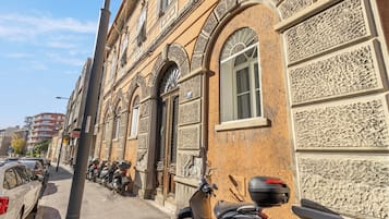 A street with parked motorcycles and cars, buildings with ornate facades, and a clear sky.