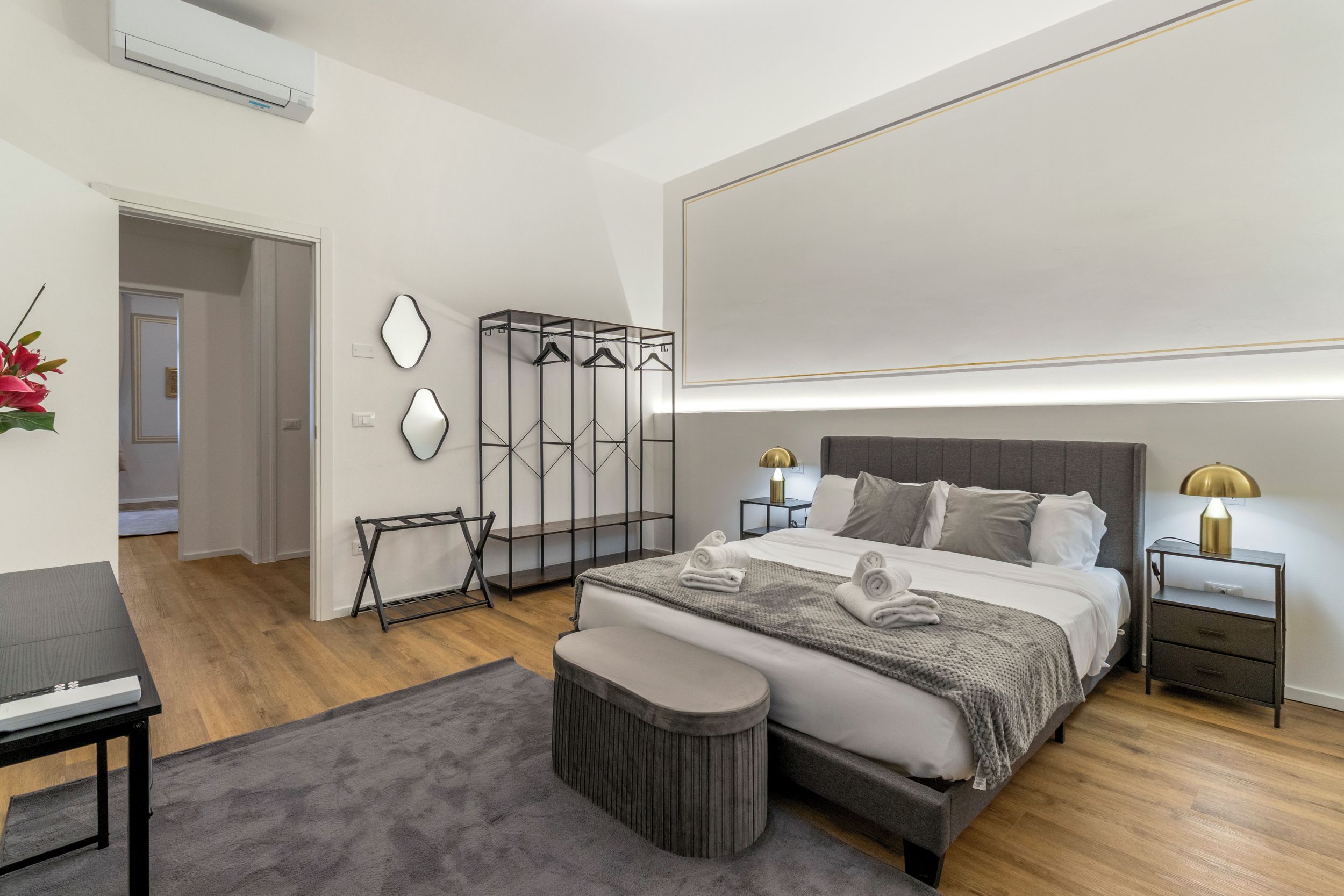 Un dormitorio moderno con una cama grande, mesitas de noche, un área de descanso y un armario.
