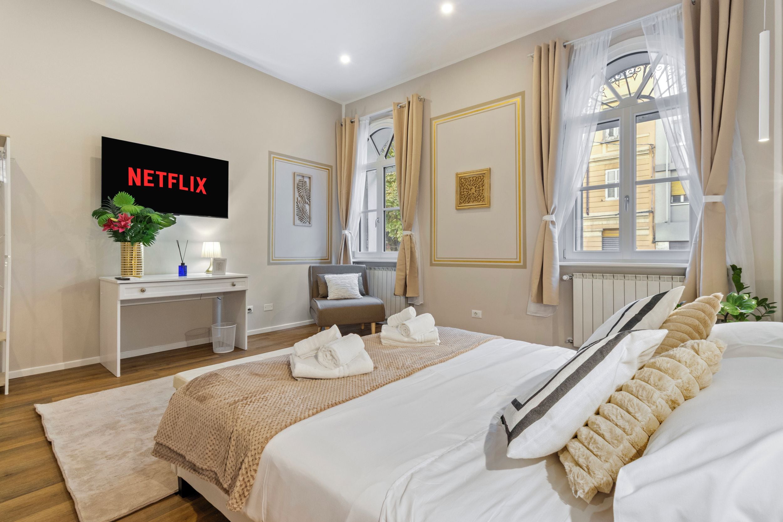 Une chambre d’hôtel avec un lit, un bureau avec une télévision, une fenêtre avec des rideaux et une vue sur l’extérieur.