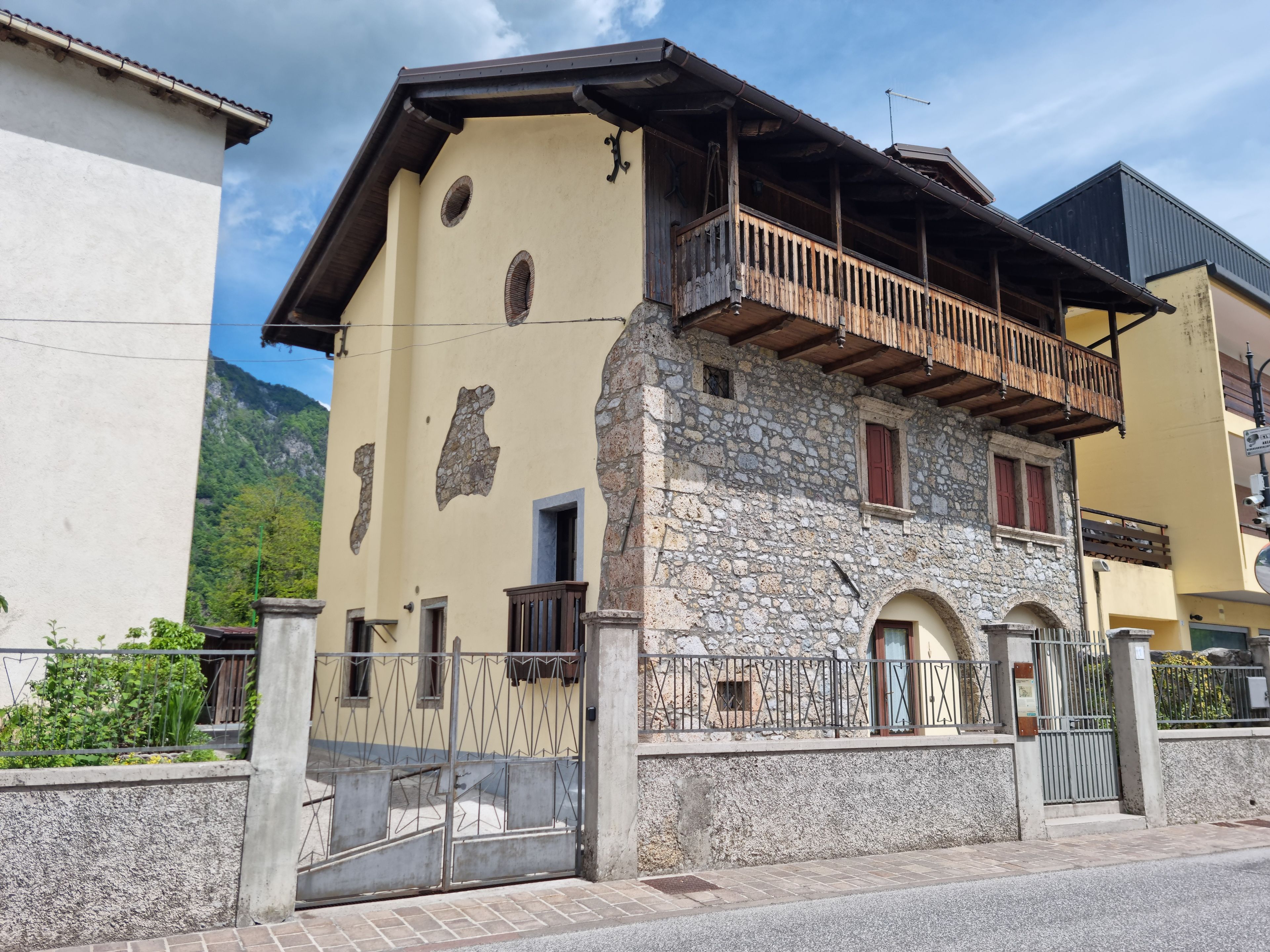 Ein zweistöckiges Gebäude mit Sandsteinfassade, Holzbalkon und einem ehrfurchtgebietenden Eingangstor.