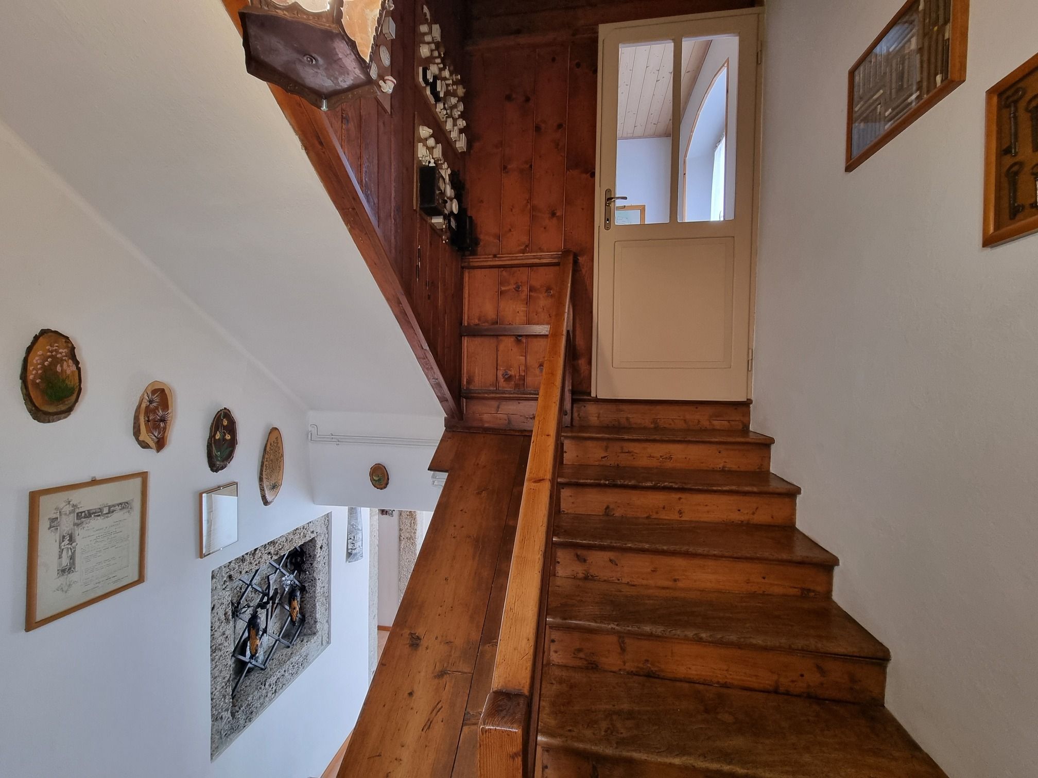 A wooden staircase with a white door at the top, surrounded by wall-mounted decorations.