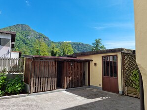 A residential area with a house featuring a wooden gate, a small porch, and a view of a mountain. - La Cjase di Tacuin - Dimore Tipiche Friulane (Ampezzo)