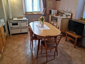 A compact kitchen with a dining table, chairs, a microwave, and a television.