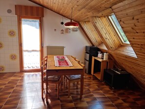 A cozy kitchen with a wooden table, chairs, a radiator, and a window. - Zoncolan Secret Escape - Wifi - Netflix - Parking (Ravascletto)