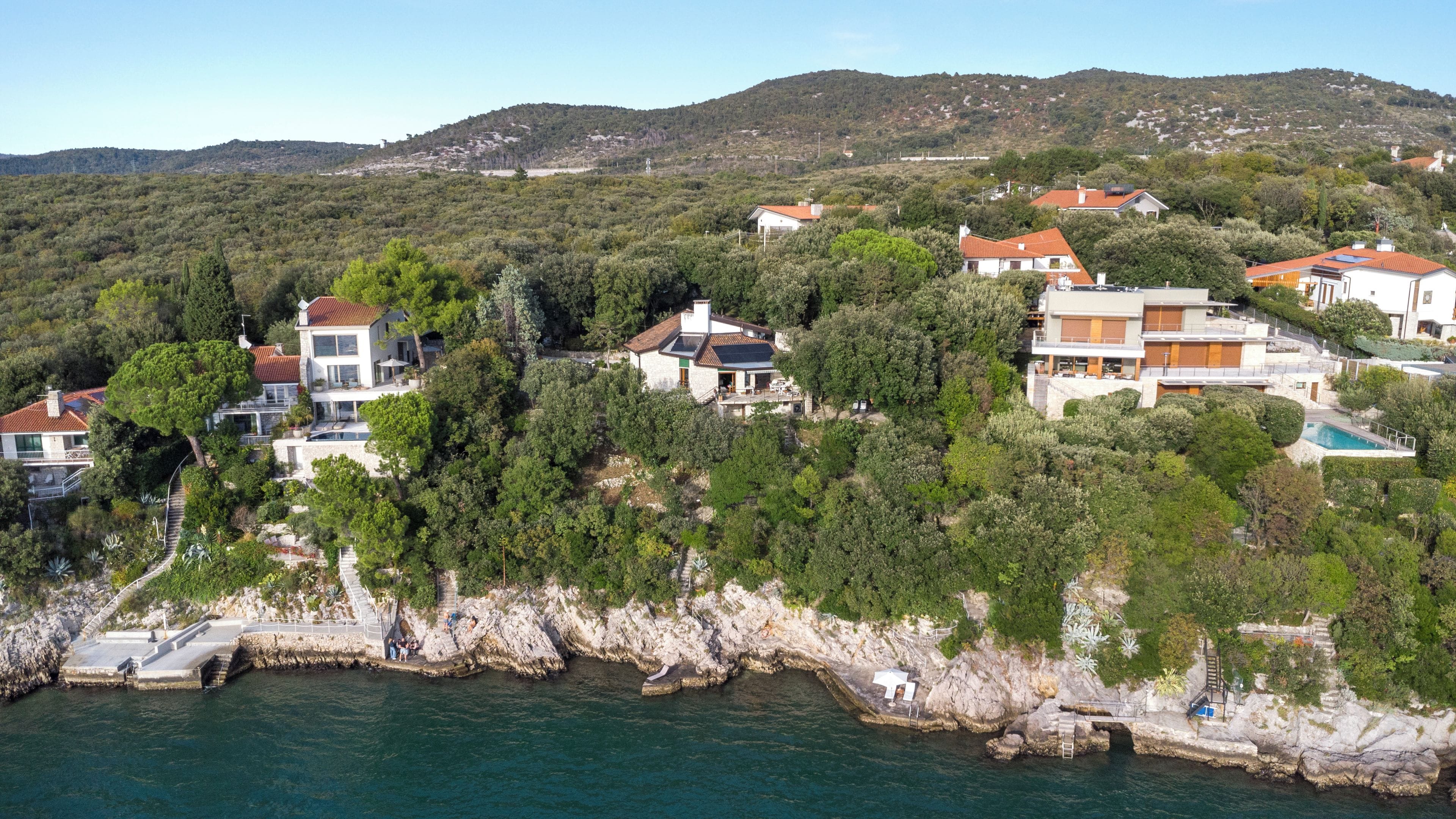 Una propiedad costera con varias casas, un litoral rocoso y una vista despejada del mar.