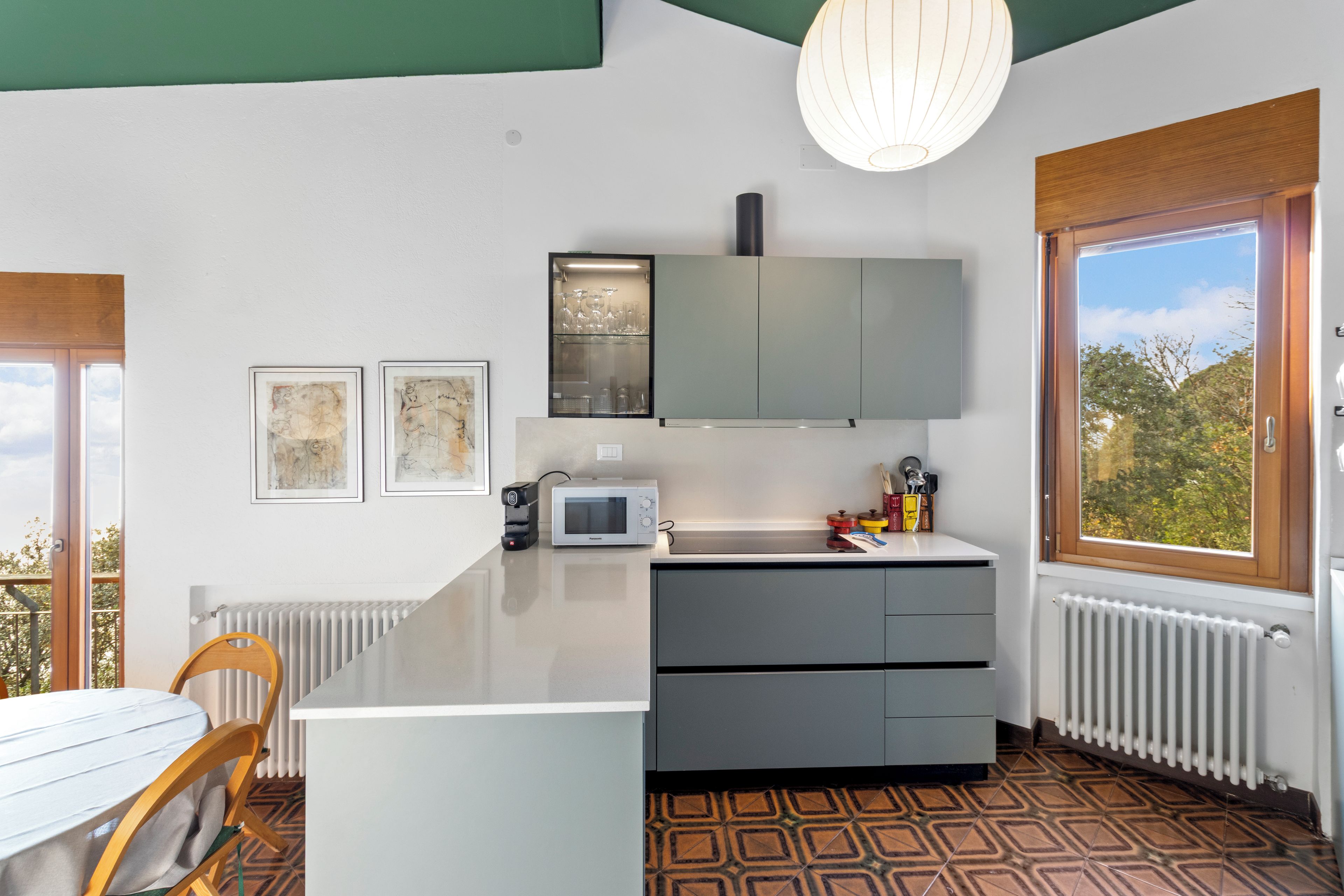 Una cocina moderna con una isla central, microondas y ventana con vistas a árboles.