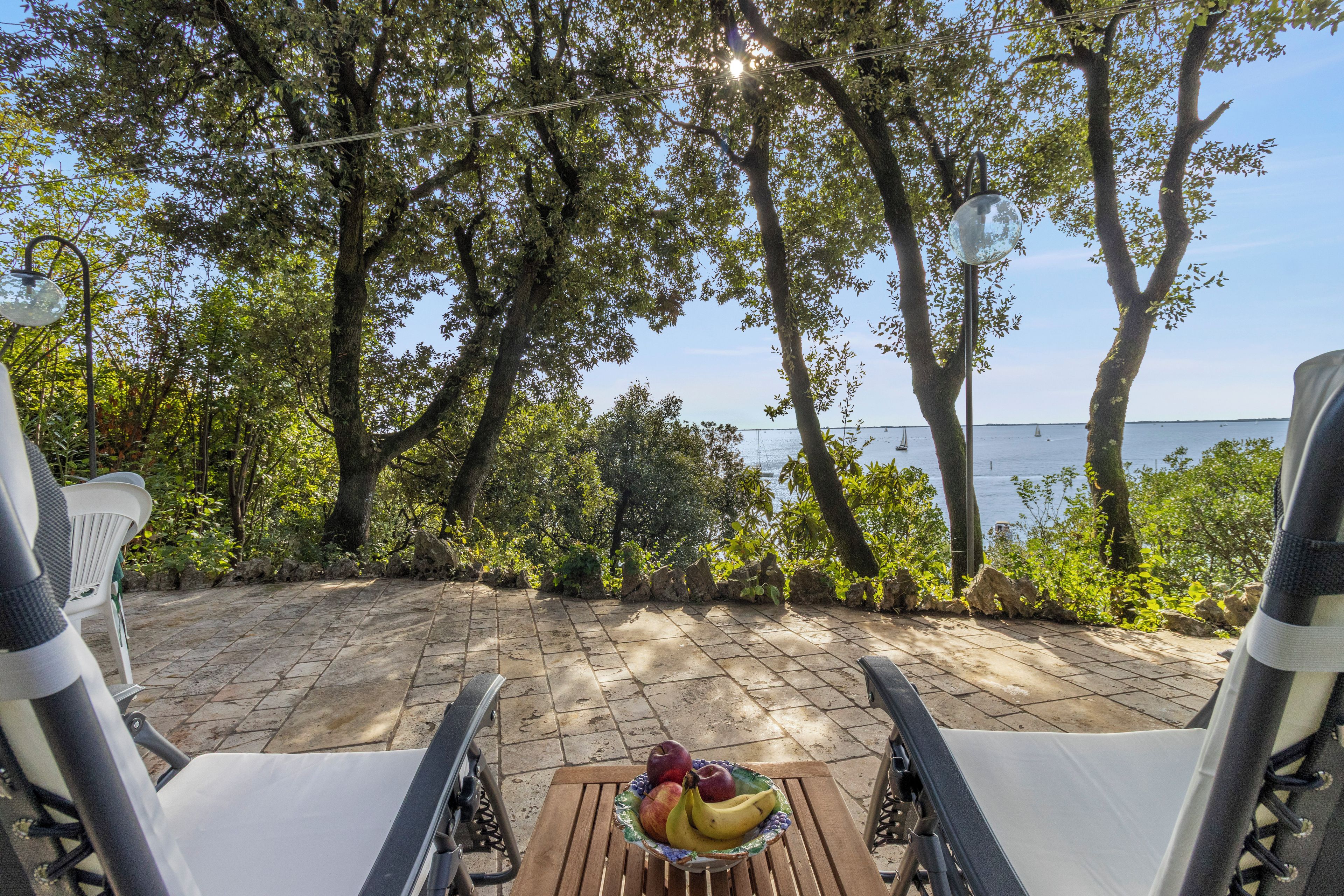 Un patio con mobiliario exterior, una mesa con fruta y vistas al mar.