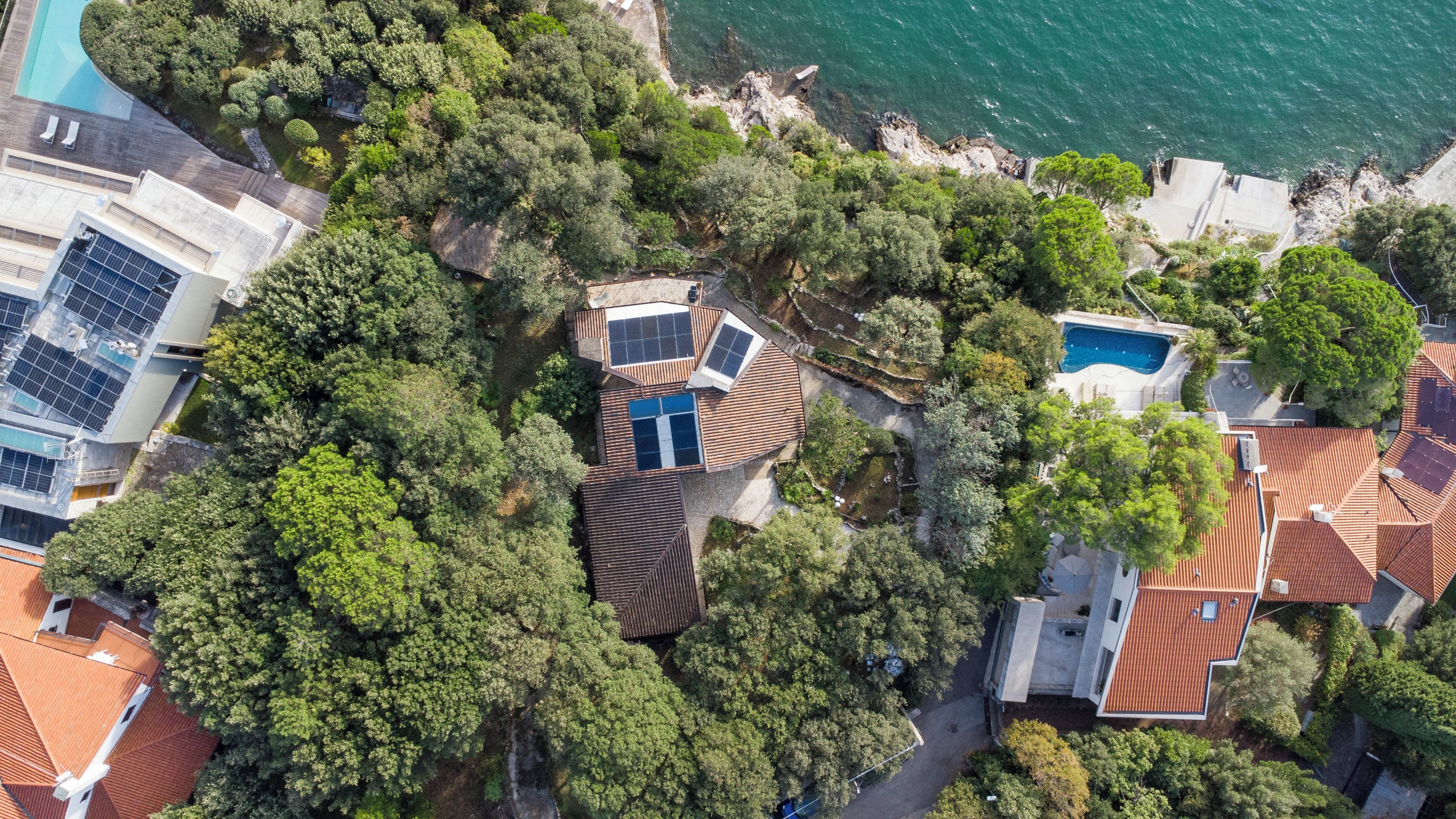 Vue aérienne d’un quartier résidentiel avec des maisons, une piscine et des panneaux solaires.