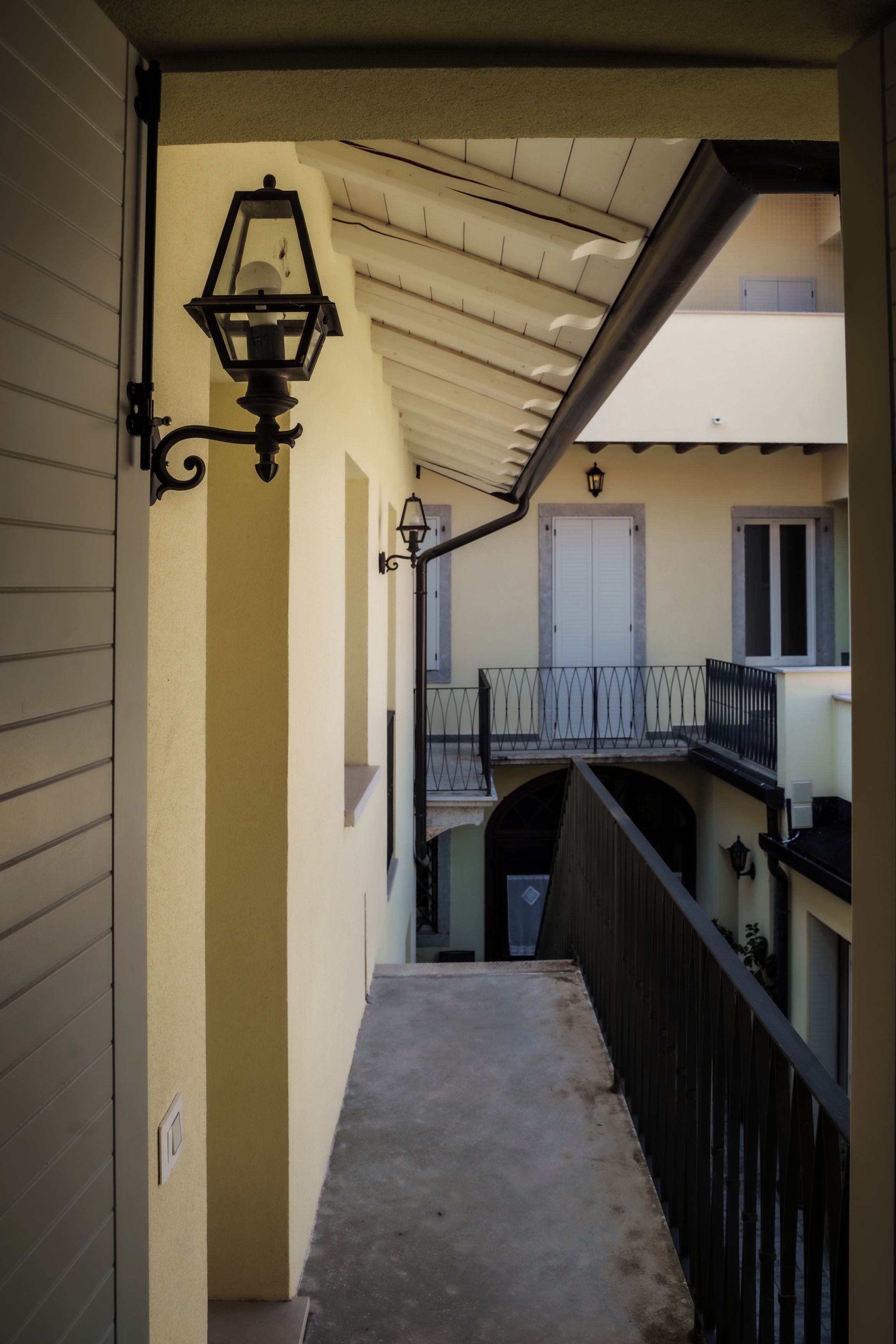 Un couloir avec une rambarde en métal, une porte et une fenêtre.