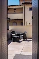 Un patio al aire libre con una mesa y dos sillas, una mesita redonda y una lámpara fijada a la pared.