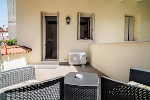 An outdoor seating area with wicker furniture, a Hisense air conditioner, and a view of the adjacent building's interior. - Urban Wine Studio Apartment con Terrazzo (Gorizia)