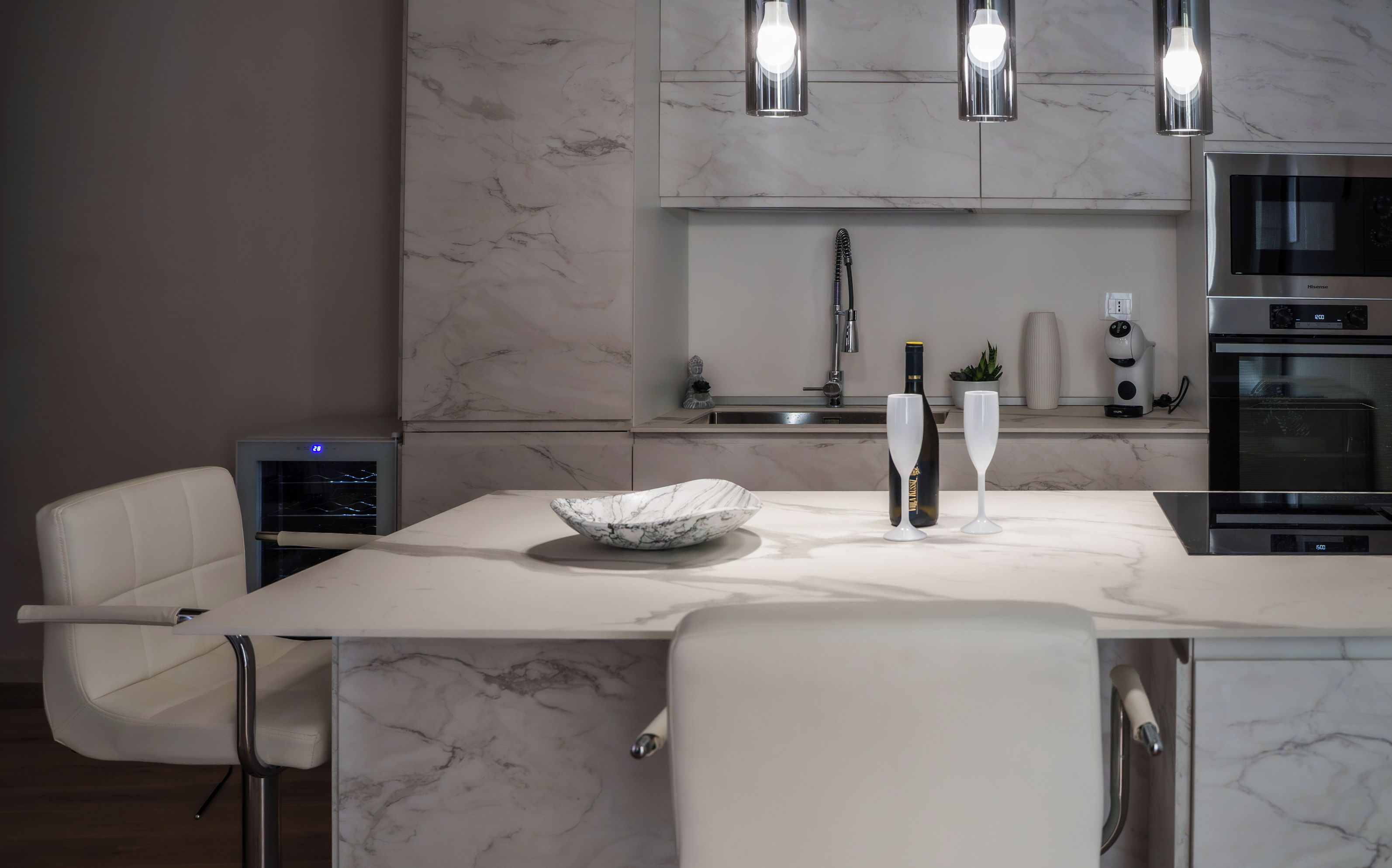 Une cuisine moderne dotée d’un plan de travail en marbre, d’un four encastré et d’une bouteille de vin.