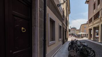 A narrow street with buildings on either side, a row of bicycles parked on the sidewalk, and a cobblestone road.