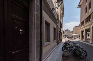 Una calle estrecha flanqueada por edificios, con una fila de bicicletas estacionadas en la acera y un camino adoquinado.
