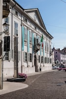 A historic building with classical architecture, a clock, and flags.