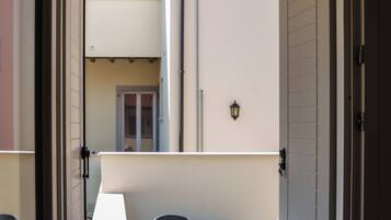 A balcony with a potted plant, a table, and chairs.