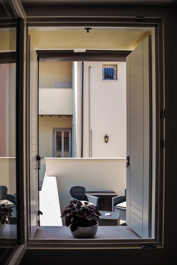 A balcony with a potted plant, a table, and chairs.