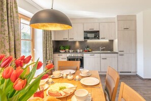 A modern kitchen with light wood cabinets, a microwave, and a dining area with a table set for two. - Holiday apartment with 2 bedrooms (Chieming)