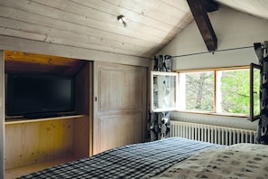 A bedroom with a television on a wooden shelf, a window with curtains, and a radiator. - Alpenflair holiday apartment Almfried 204 (Oberstdorf)