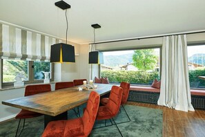 Ein Essbereich mit einem Holztisch, roten Sitzmöglichkeiten und Pendelleuchten.