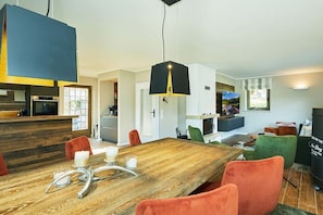 Een moderne eethoek met een houten tafel, rode stoelen en een zwarte hanglamp.