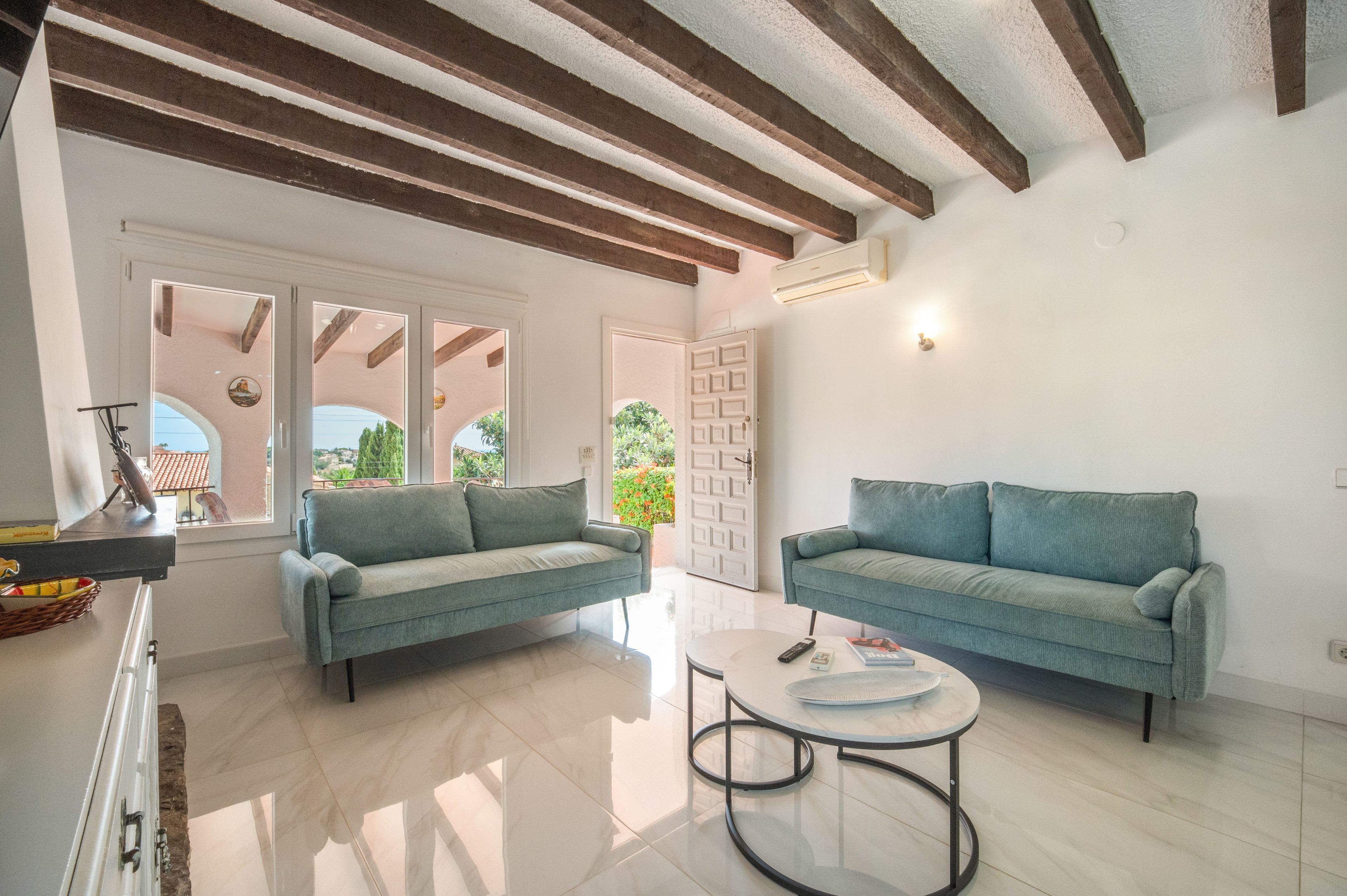 A modern living room with two sofas, a coffee table, and a view through a glass door.