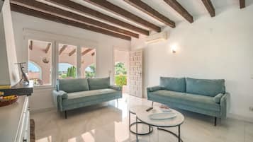 A modern living room with two sofas, a coffee table, and a view through a glass door.