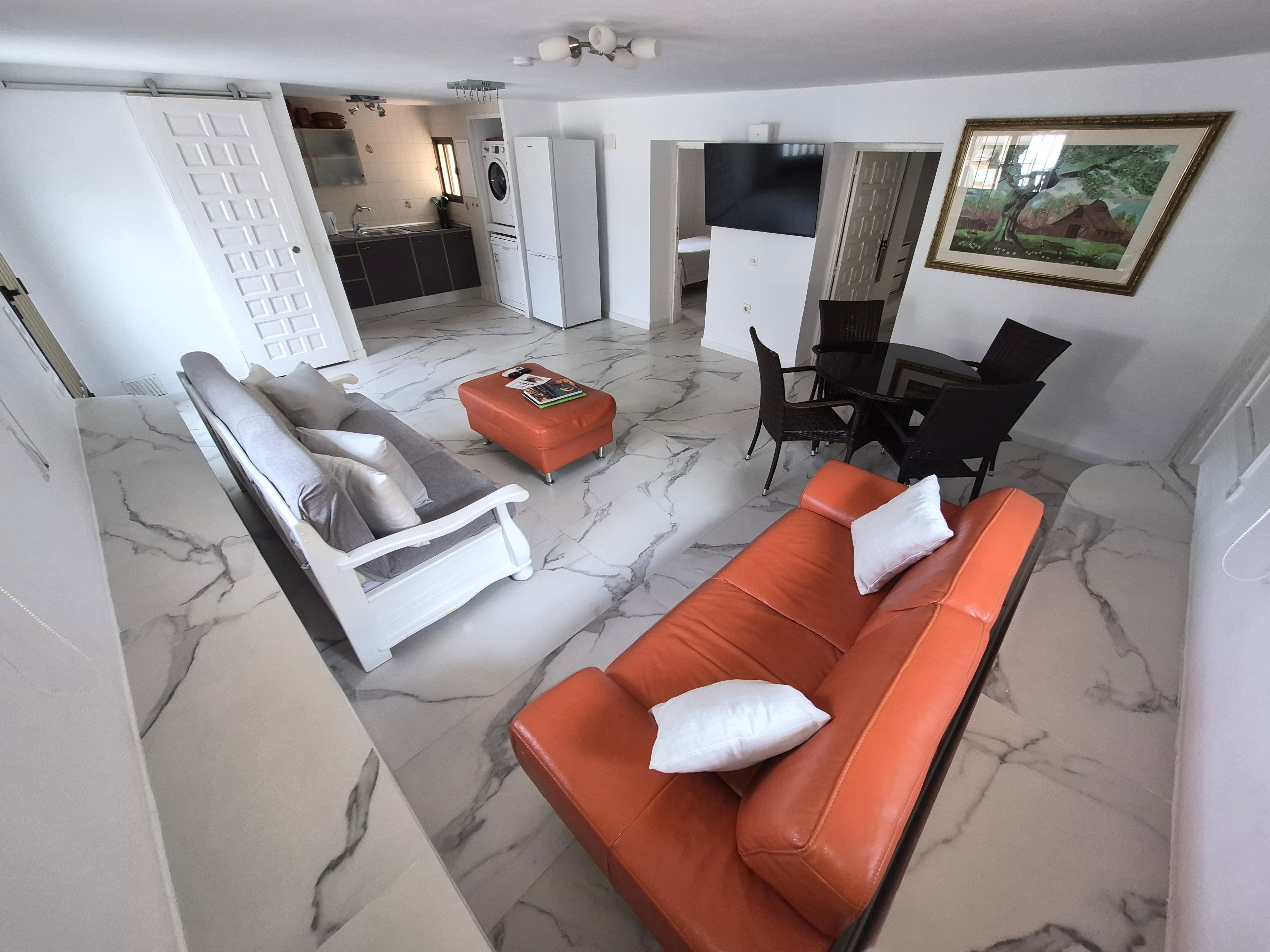 A living room with a sofa, ottoman, and a dining area with chairs.