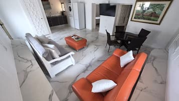A living room with a sofa, ottoman, and a dining area with chairs.
