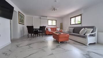 A spacious living area with a dining table, chairs, a sofa, and a coffee table.