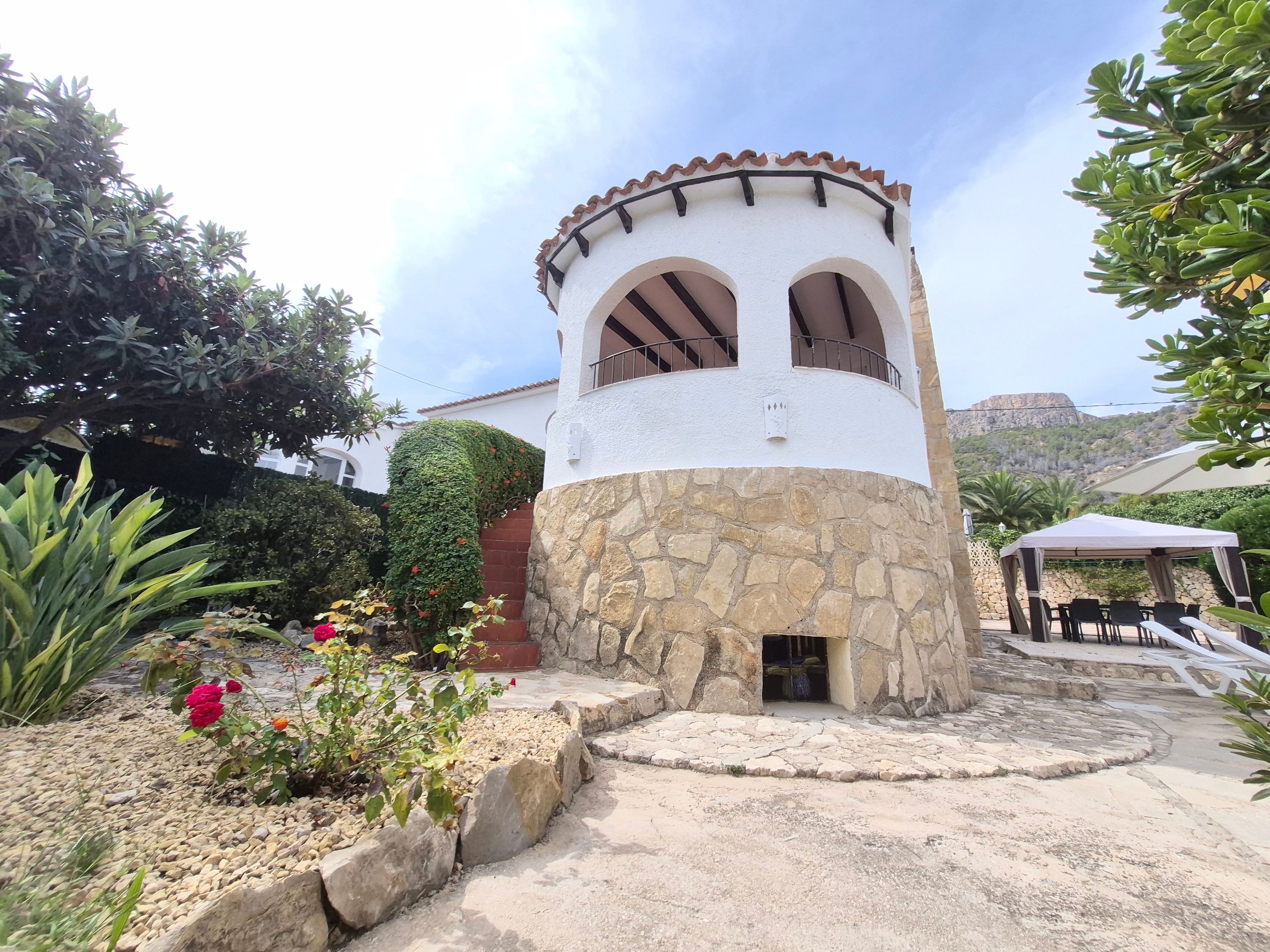 A white building with a stone base, arched windows, and a small door.