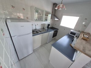 Eine Küche mit Kühlschrank, Spüle, Mikrowelle und einem Fenster.