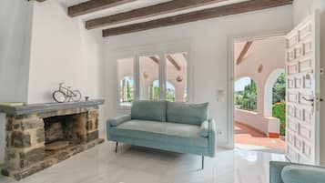A room with a stone fireplace, a sofa, and a view through a glass door to an outdoor area.