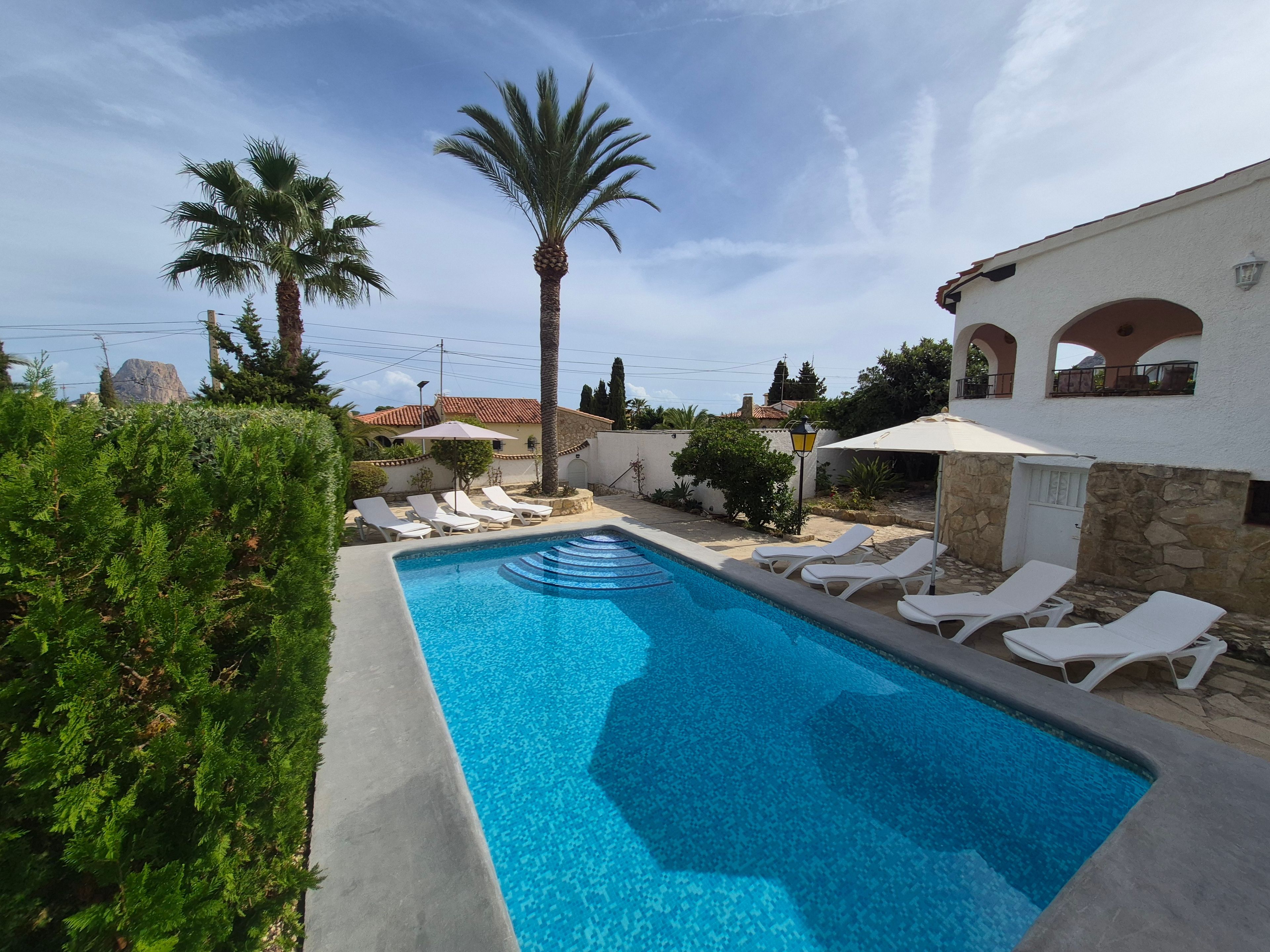 A swimming pool with lounge chairs and a stone wall.