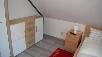 A bedroom with a bed, a nightstand, a dresser, and a red rug.