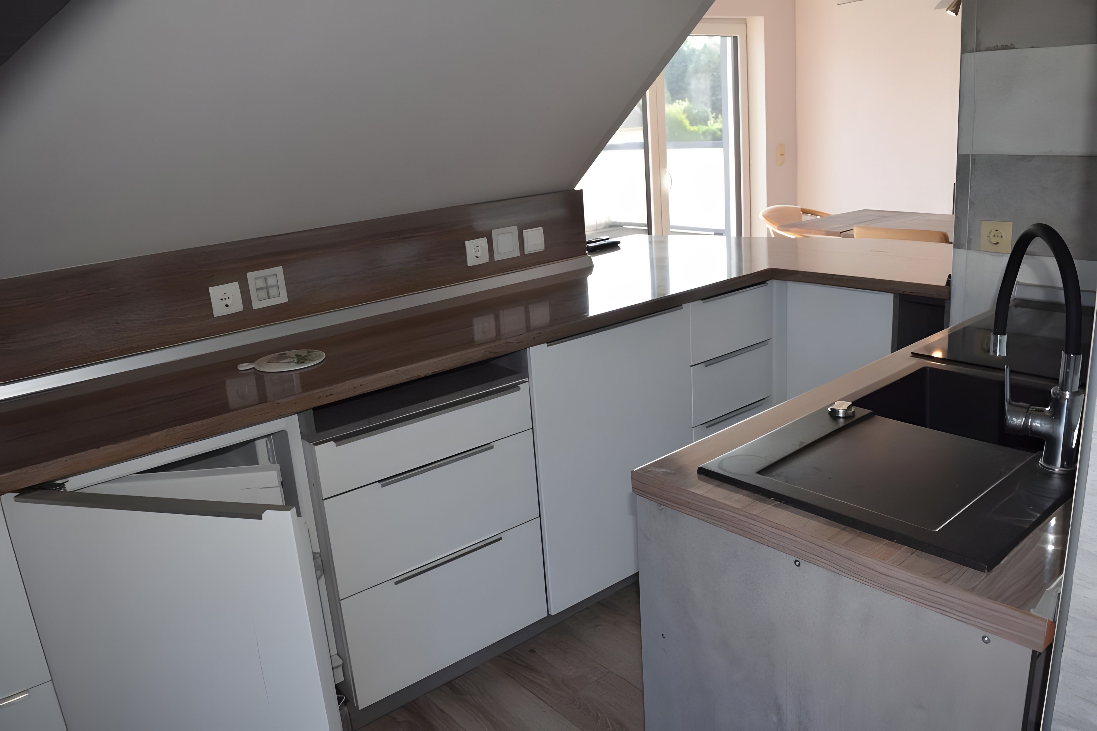 A modern kitchen with white cabinetry, a wooden countertop, and a stainless steel sink.