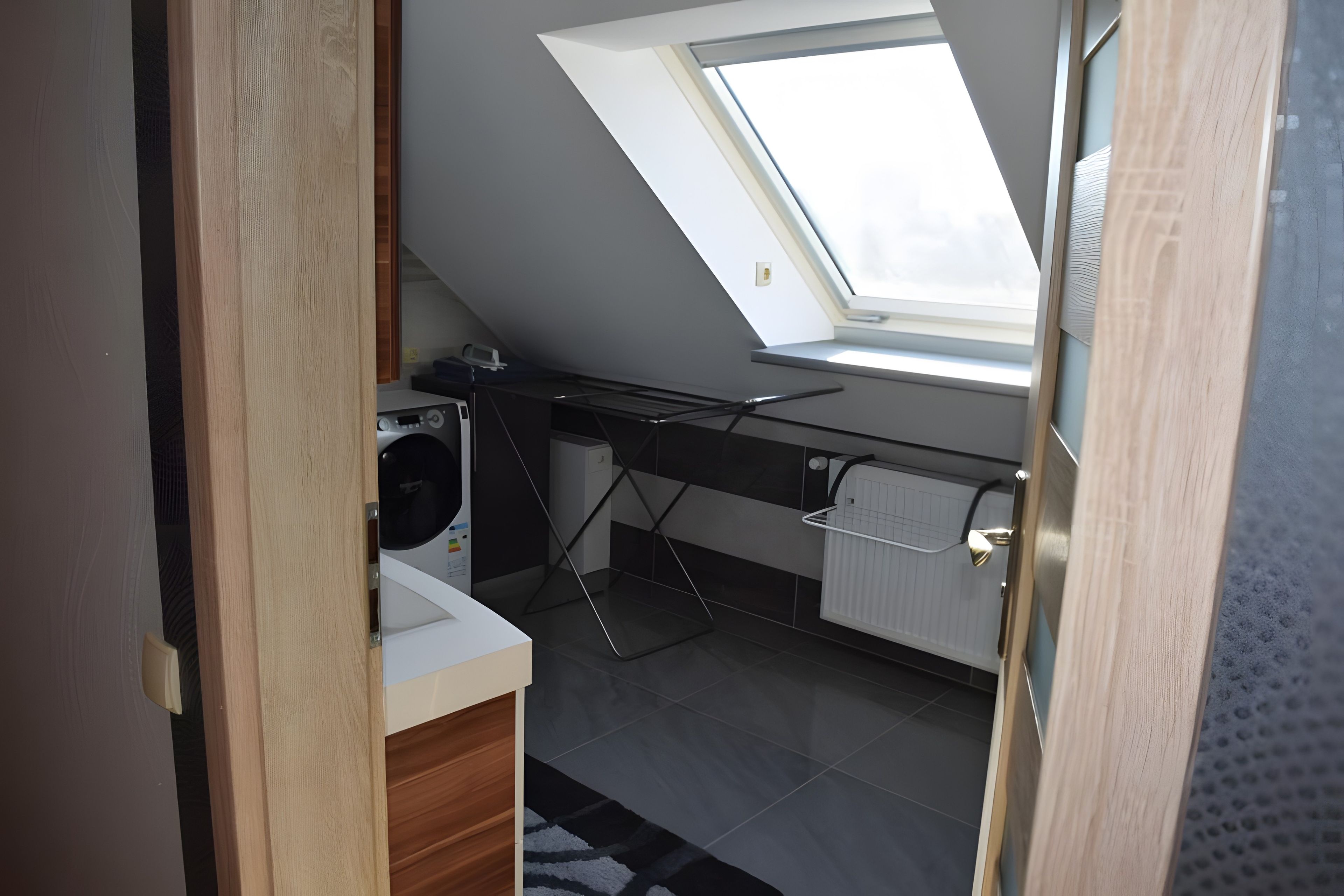 A compact kitchen with a skylight, a washing machine, and a radiator.