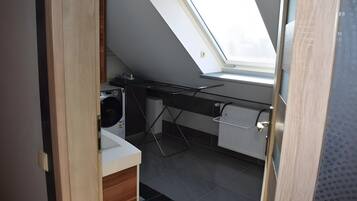 A compact kitchen with a skylight, a washing machine, and a radiator.