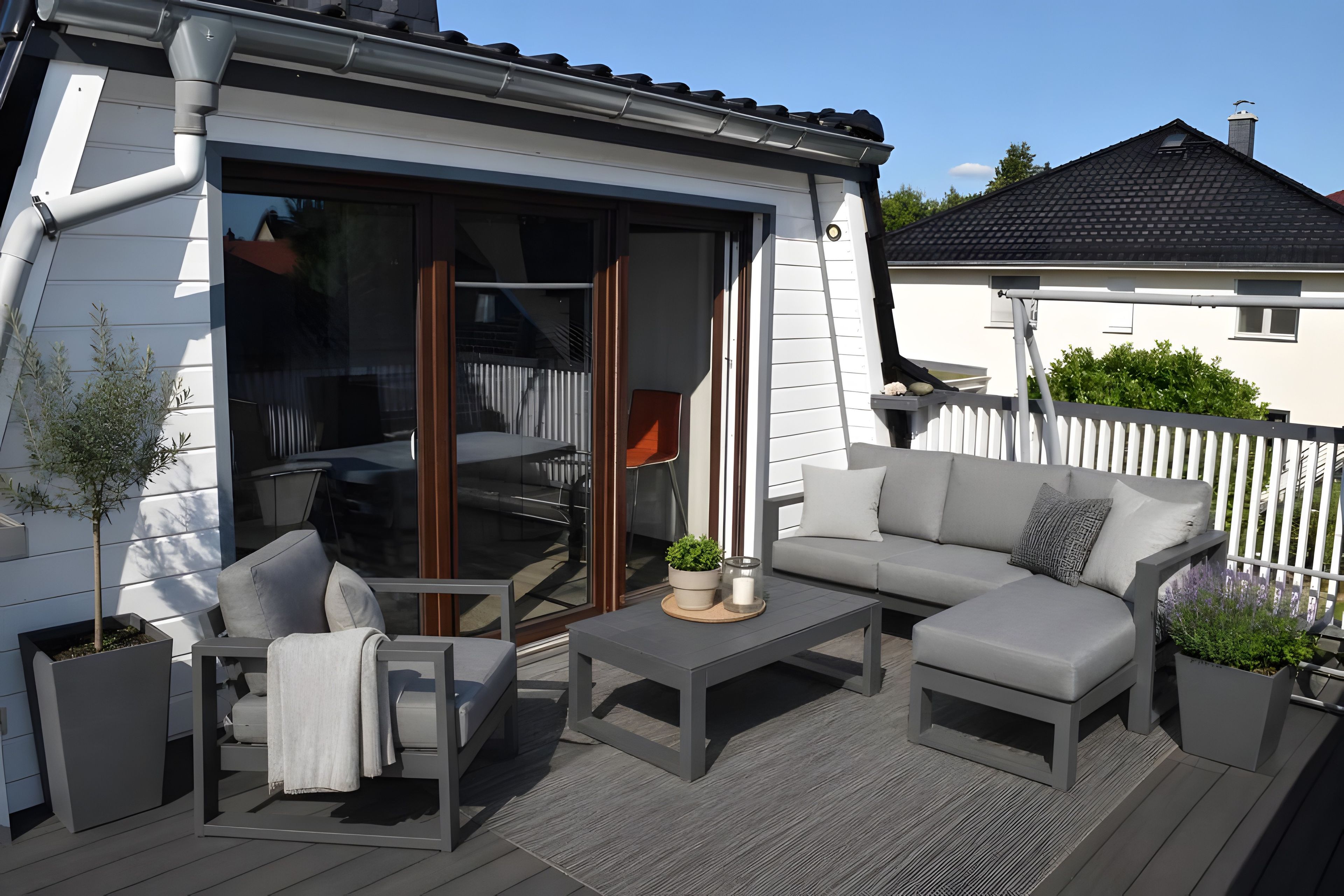 Ein Terrassenbereich im Freien mit einer Couch, Stühlen und einem Tisch.