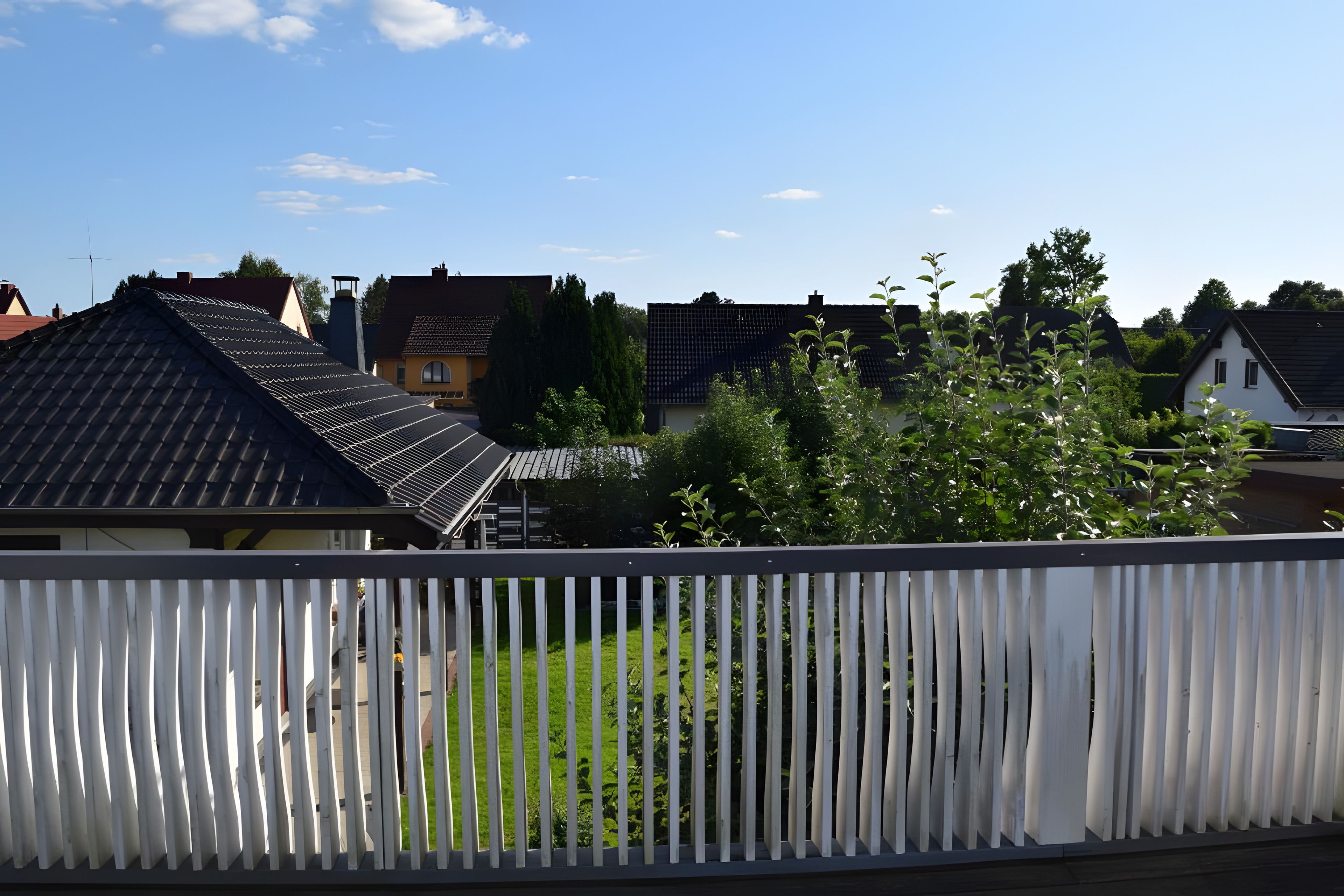 Ein Wohngebiet mit Häusern, einem gr ünen Rasen und einem weißen Zaun.