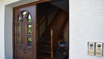 A wooden door with a glass panel, a staircase with wooden railings, and a white brick wall.