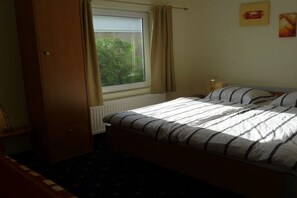 A bedroom with a bed, a window with curtains, a radiator, and a wardrobe. - Holiday home in Lemmer with swimming pool (Lemmer)