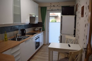 A compact kitchen with white cabinets, a black stove, and a small dining area with a table and chairs.